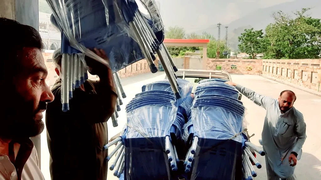 Men unloading stacks of new blue chairs.