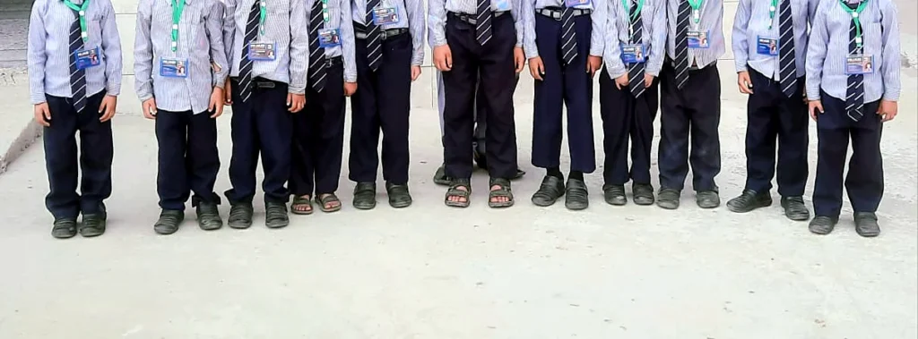 A row of pupils in grey school uniforms.